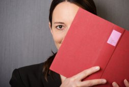 Eine Frau verdeckt ein Auge mit einem Buch | © contrastwerkstatt - stock.adobe.com